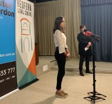 A young woman stands in front of a microphone.