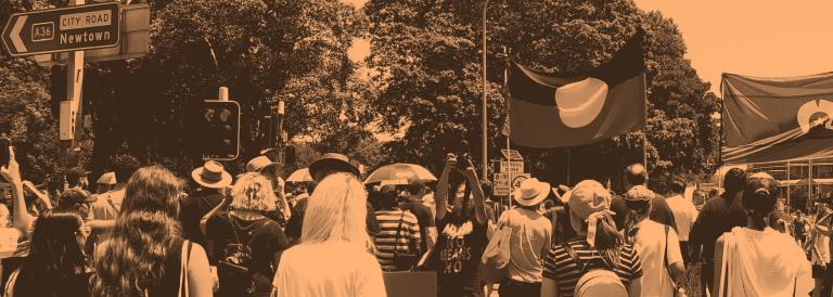 Protesters on a main road holding Aboriginal flags