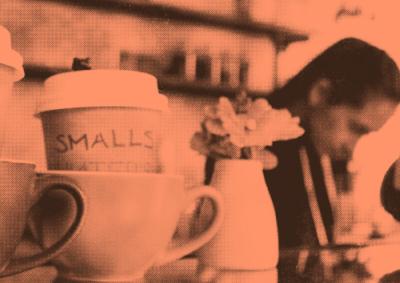 Coffee cups with a cafe worker in background red tinted image