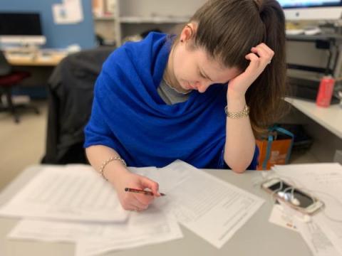 A distressed woman holds a pencil and looks at financial papers with her hand on her head