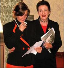 Two woman stand together one is holding a microphone giving a speech