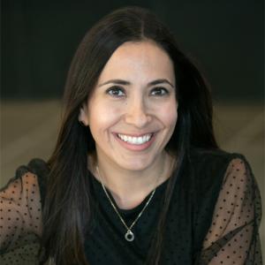 Smiling woman with long brown hair wearing long-sleeve black lace top