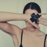 Domestic Violence and Financial Abuse thumbnail - Woman with arm across face in defensive position with taped cross