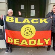 Two women holding an Aboriginal flag that says 'Black and Deadly'