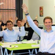 Group of university students excitedly raising arms while seating