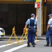 Three police people standing in front of their car at a road closure
